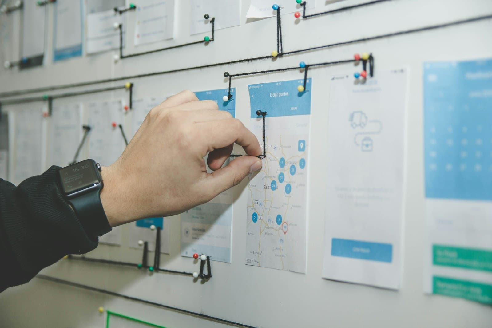 User-flow screens pinned to a planning wall and connected with thread